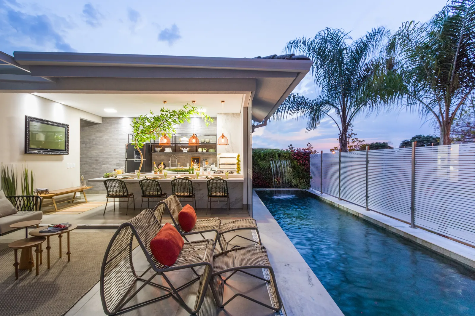 Photo: the veranda and pool at dusk, with the water feature and garden wall lit