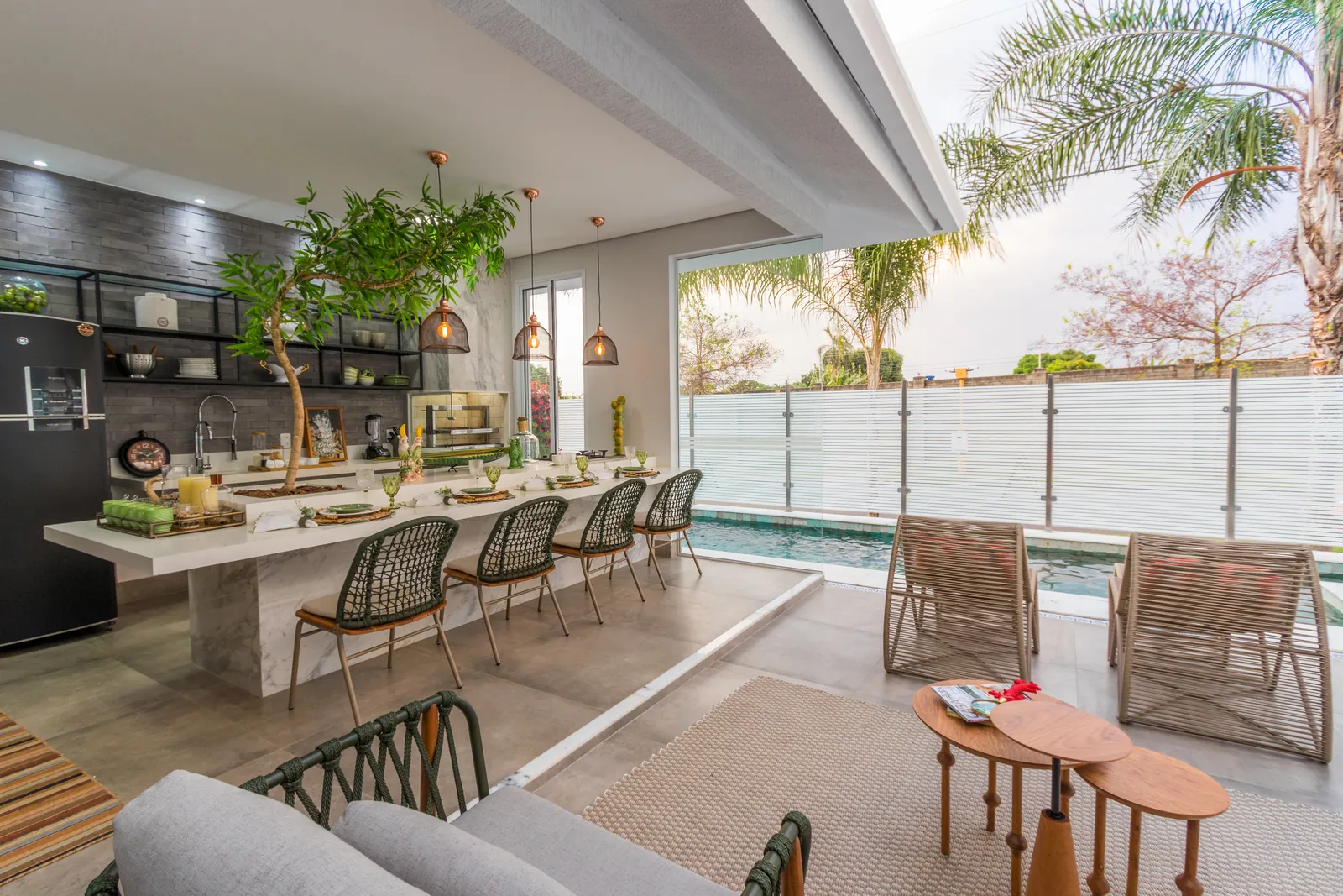 Photo: outdoor kitchen with a stone island, woven bar chairs and open black shelving