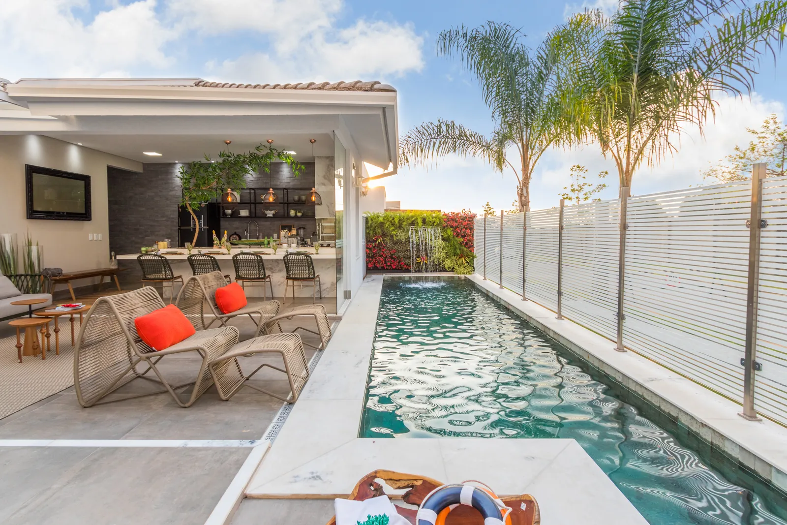 Photo: covered gourmet veranda with lounge chairs beside a long lap pool and palms